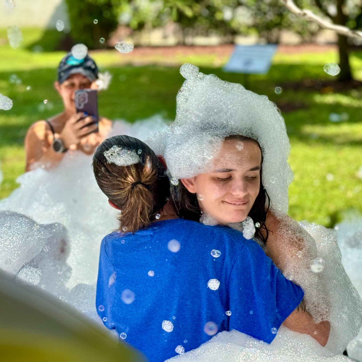 Friends hugging and having fun covered in foam